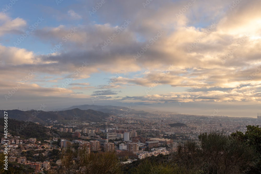 Panorama of Barcelona from the air in the early morning. City with shadows from the clouds. Dramatic sky over the city. Autumn in Barcelona, Spain.