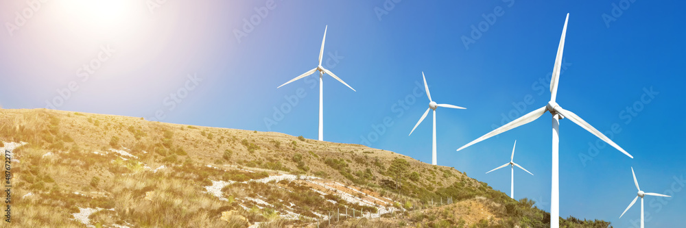 Wind turbines on a blue sky background. Wind farms produce clean renewable energy in an environmentally friendly way. The concept of green renewable energy sources Wind turbines on a blue sky background. Wind farms produce clean renewable energy in an environmentally friendly way. The concept of green renewable energy sources