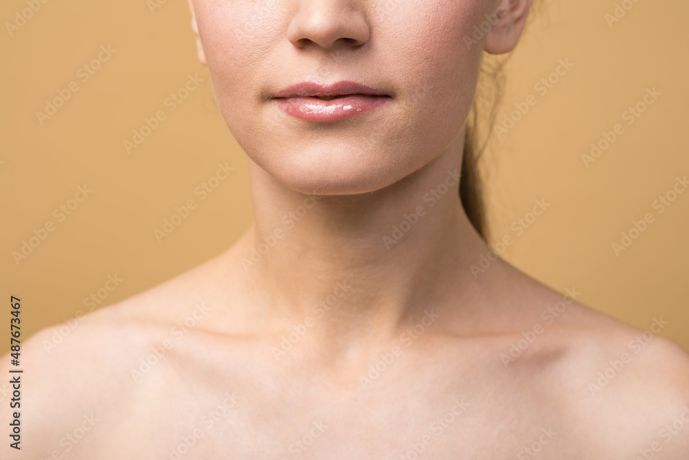 Close up of the lips of a caucasian girl with clean skin isolated on a beige studio background. Skin care and beauty concept. Close up of the lips of a caucasian girl with clean skin isolated on a beige studio background. Skin care and beauty concept.