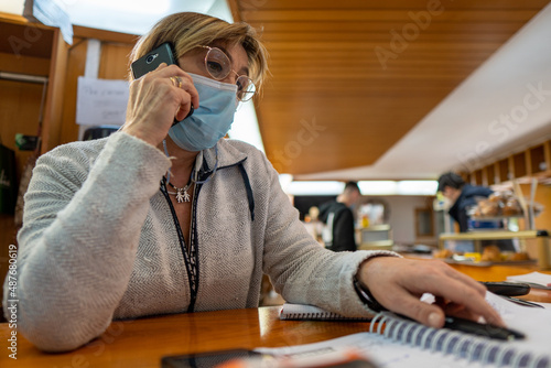 Old woman with mask and glasses organizing orders in a bar