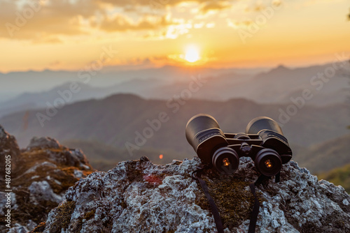binoculars on top of rock mountain at sunset