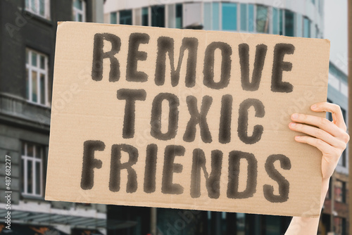 The phrase " Remove toxic friends " on a banner in men's hand with blurred background. Unity. Union. Risk. Trust. Fake. Hard. Bad. Avoid. Two. Meet. Person. Social. Career. Destroy. Mental. Status © AndriiKoval