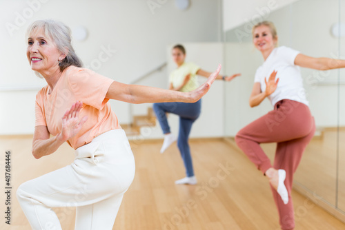 Cheerful mature woman with family learning swing steps at dance class