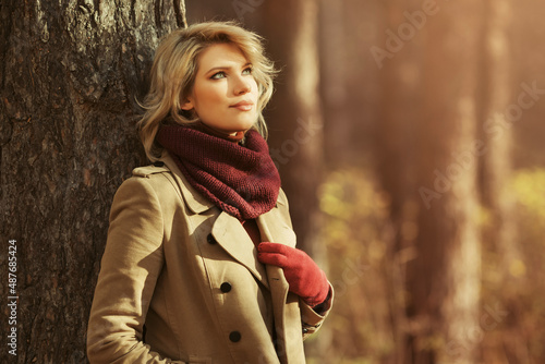 Young blonde woman in classic beige coat and burgundy scarf
