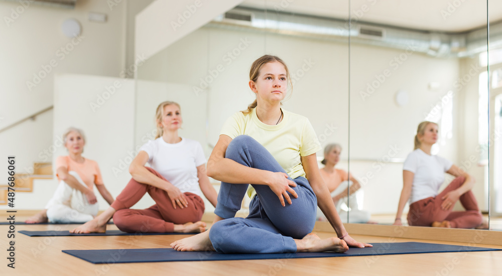 Obraz premium Portrait of positive school girl training stretching workout in modern studio