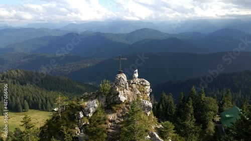 Drone flying around a summit cross and a capricorn statue with view on the valley of Lenggries and the mountains of Brauneck in the bavarian Alps photo