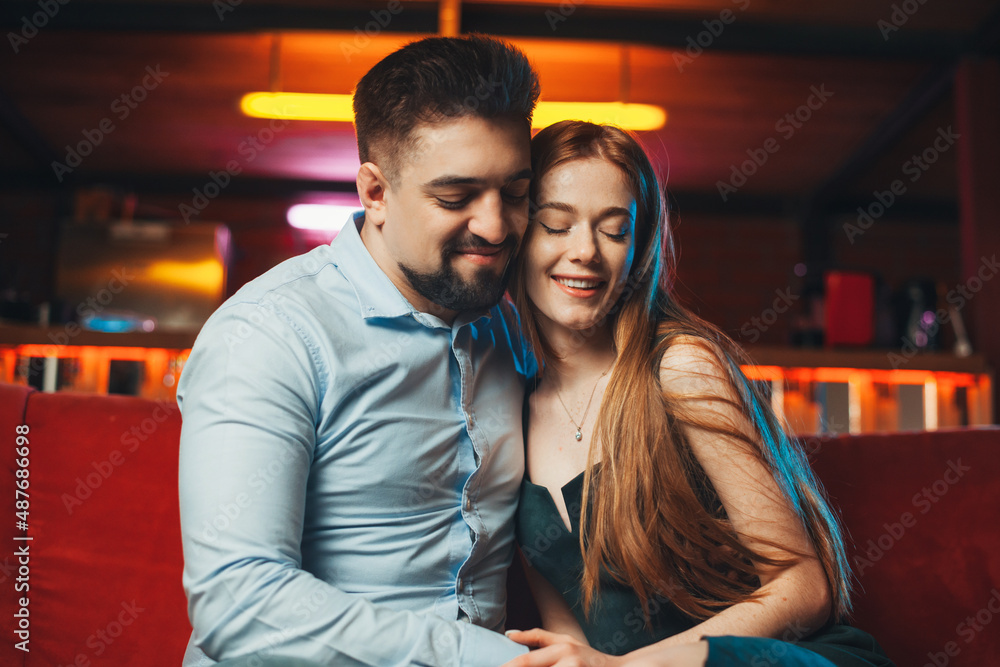 Lovely caucasian couple in love embracing on the sofa at restaurant. Beautiful female person. Lovely caucasian couple in love embracing on the sofa at restaurant. Beautiful female person.