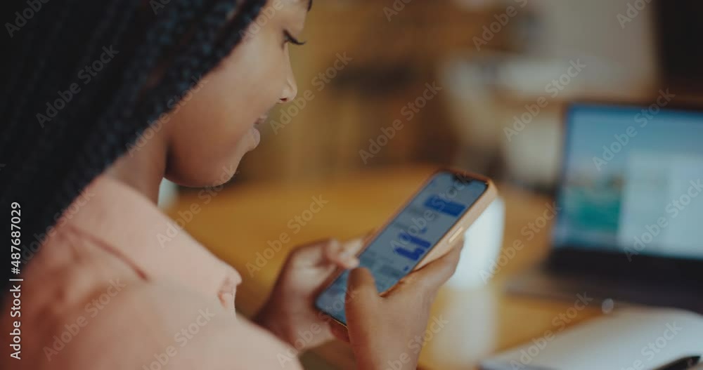 Beautiful young black woman texting on her mobile phone, working remotely in coffee shop