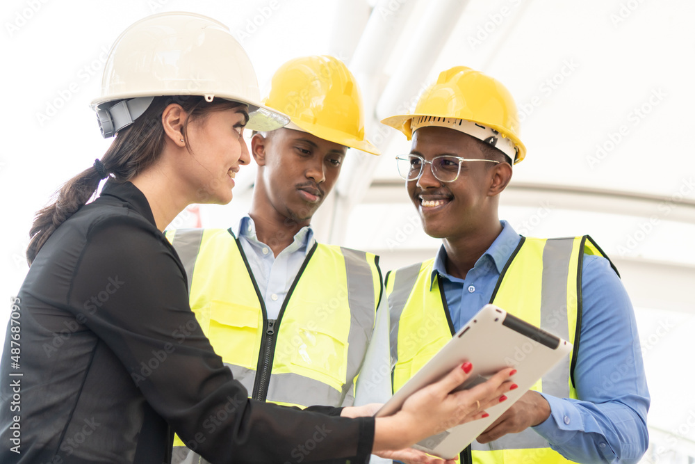 Group of Engineer Worker Wearing Safety Uniform and Hard Hat Uses Tablet Computer. Happy Successful. Businesswomen working with tablet checklist Group of Engineer Worker Wearing Safety Uniform and Hard Hat Uses Tablet Computer. Happy Successful. Businesswomen working with tablet checklist