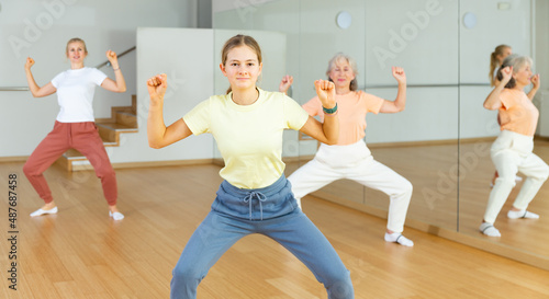 Young positive teenager girl dancing during group class in dance center