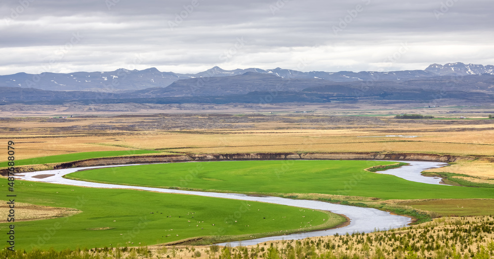 Hvita river flowing through fields and meadows in Iceland countryside.