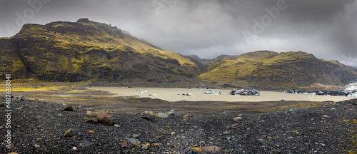 Panoramic view of hills around Svinafellsjokull glacier in southern Iceland, floating ice in the lake, overcast sky .