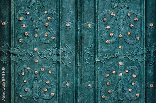 An old green metal door with an openwork ornate pattern. Vintage background closeup. Medieval forging technologies. © shchus