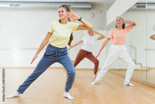 Teenage girl performing dance during group training in studio.