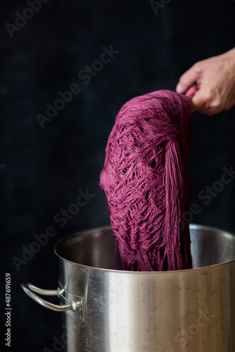 A woman's hands shows a natural dye called cochineal that is used to dye fibers such as yarn and fabrics, against a solid black background. photo