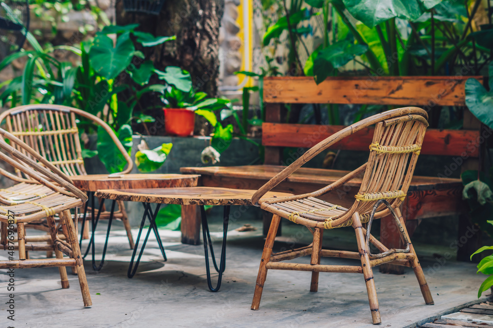 Obraz premium Cozy garden open air tropical style terrace wood bench chair table rattan wicker eco furniture. Warm mood summer nature day. Modern decor interior atmosphere relax outdoor recreation dining area