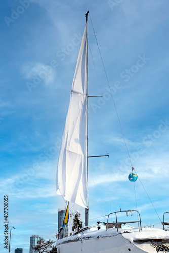 A pleasure yacht in the winter parking lot against the backdrop of the city landscape