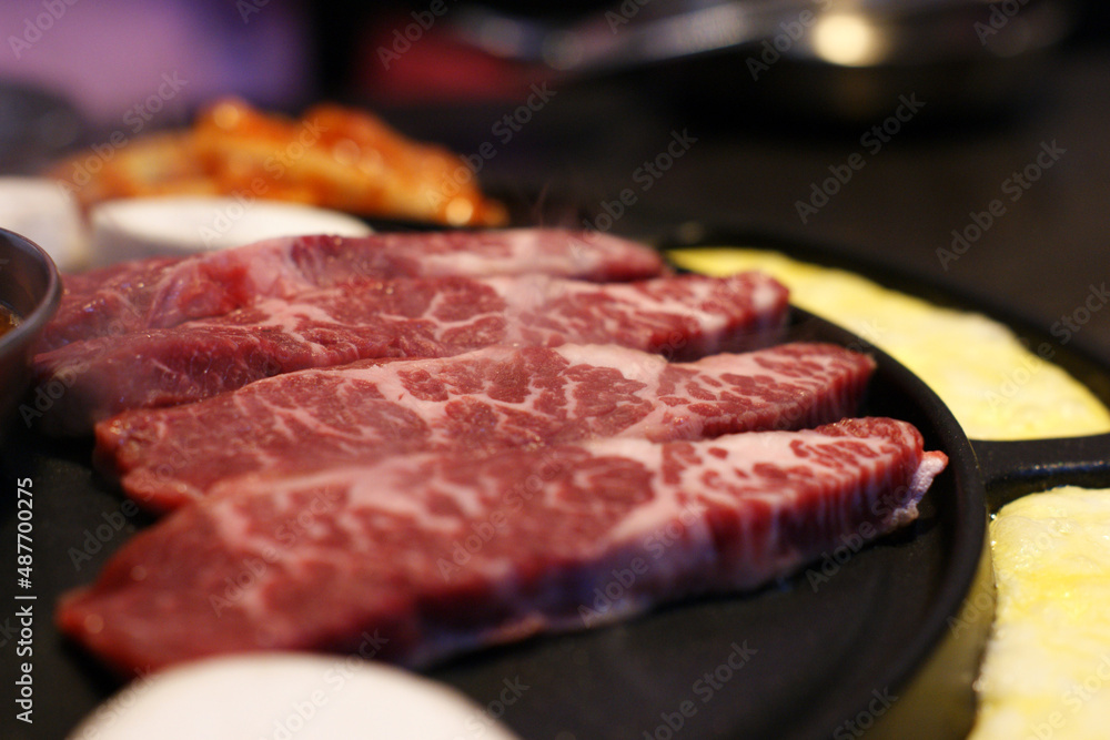 Red raw meat is being baked on an iron plate.