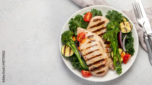 Grilled chicken with vegetables on light background.