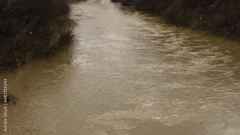 A muddy river with brown water. Slow current. A muddy river during a winter flood A muddy river with brown water. Slow current. A muddy river during a winter flood