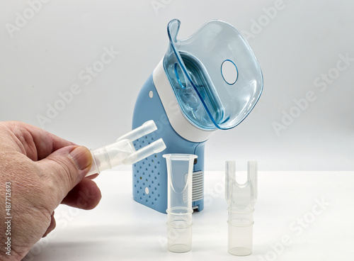 Portable compressor nebulizer on white table. Medical equipment for inhalation therapy, asthma, bronchitis.