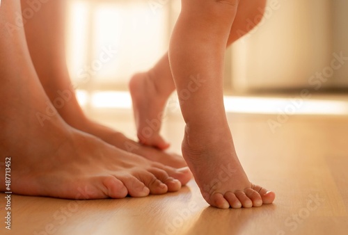 A mother helping her baby learn how to walk. First baby steps. Child development and milestones. photo