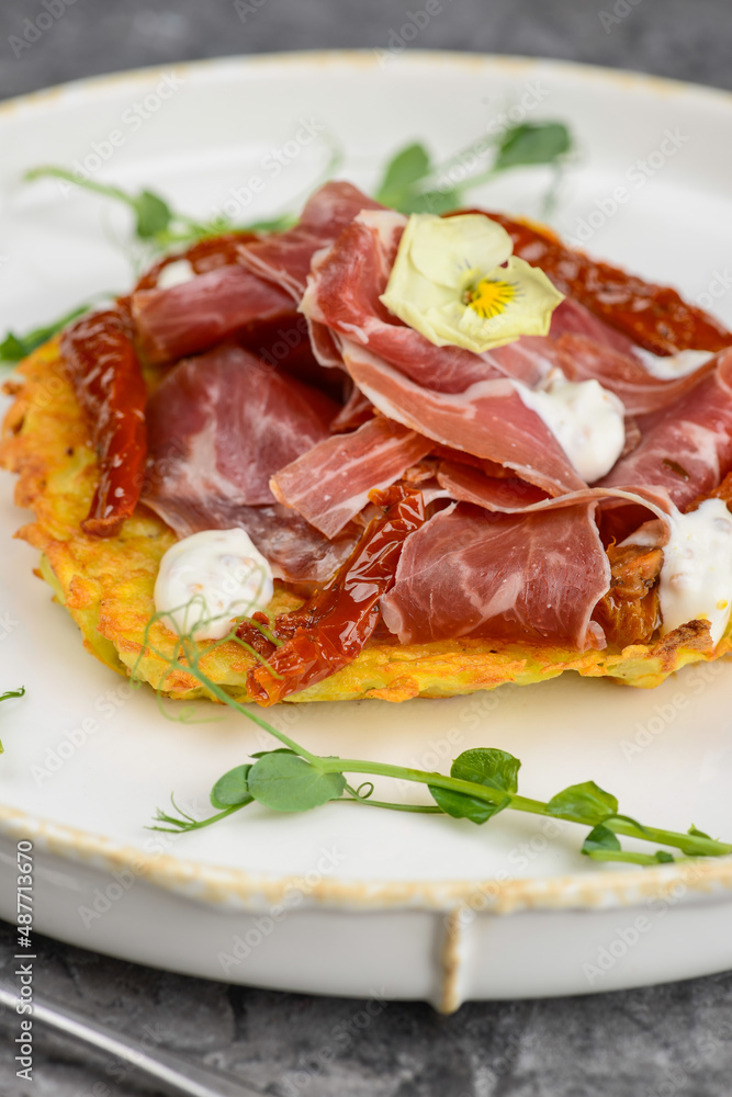 dish with potato and hammon pancake and dried peppers on a gray background
dish with potato and hammon pancake and dried peppers on a gray background