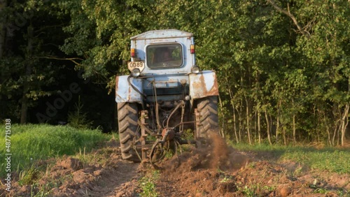 Slow motion camera view of old russian tractor harvesting potatoes. Old soviet techniq. Sunny autumn evening. photo