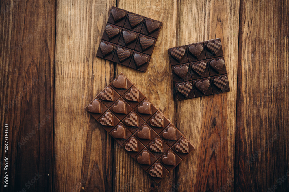 Delicious sweet pieces chocolate on wooden background shape of heart Delicious sweet pieces chocolate on wooden background shape of heart