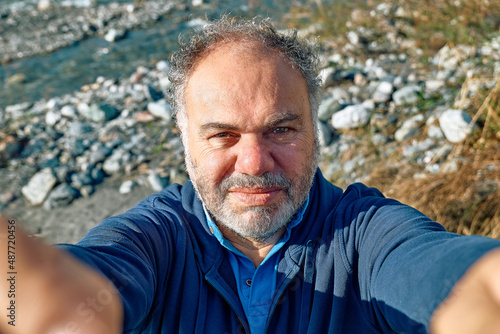 Happy, smiling mature bearded man making a selfie on seaside background. Concept of leisure activities,tourism, lifestyle e nature.