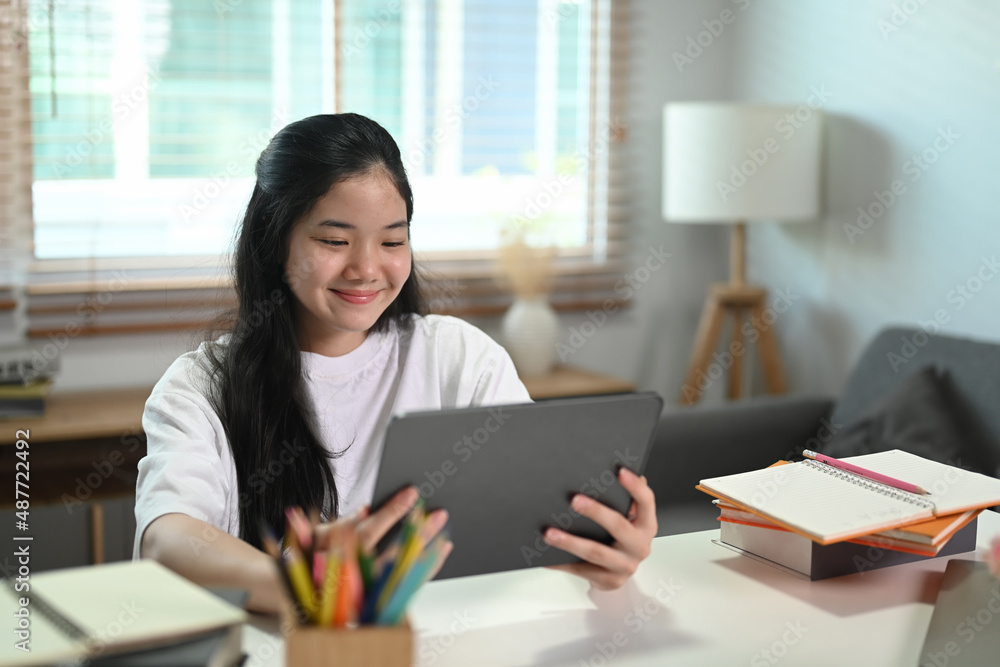 Smiling asian girl learning online in virtual classroom on digital tablet at home. Smiling asian girl learning online in virtual classroom on digital tablet at home.