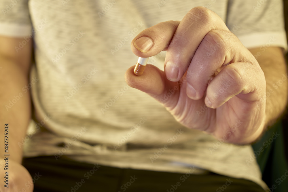 Fototapeta premium a man holds a pill in his hand in front of him