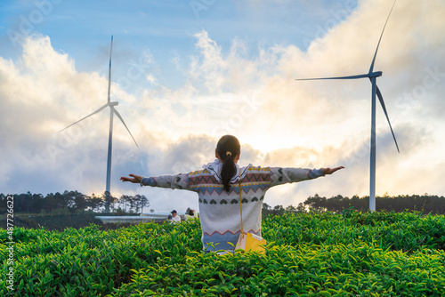 Happy woman holds her hand in a tea hill at Cau Dat, Dalat, Vietnam, morning scenery on the hillside of tea planted in the misty highlands below the beautiful valley. photo