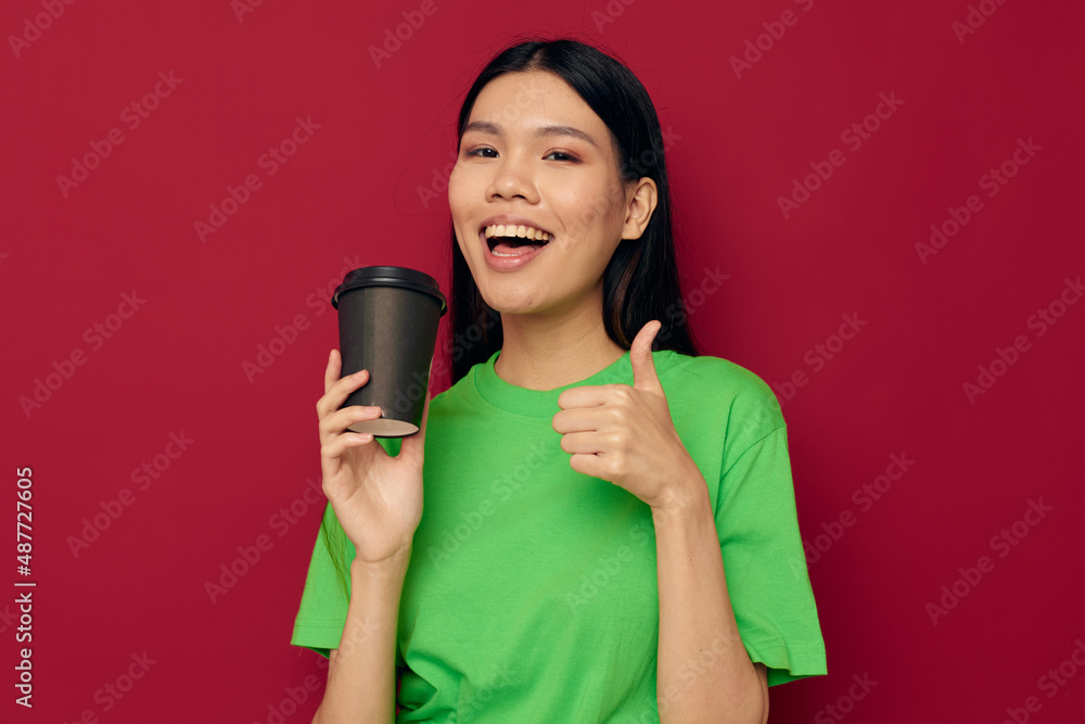 Portrait Asian beautiful young woman in a green t-shirt a glass of drink fun isolated background unaltered Portrait Asian beautiful young woman in a green t-shirt a glass of drink fun isolated background unaltered