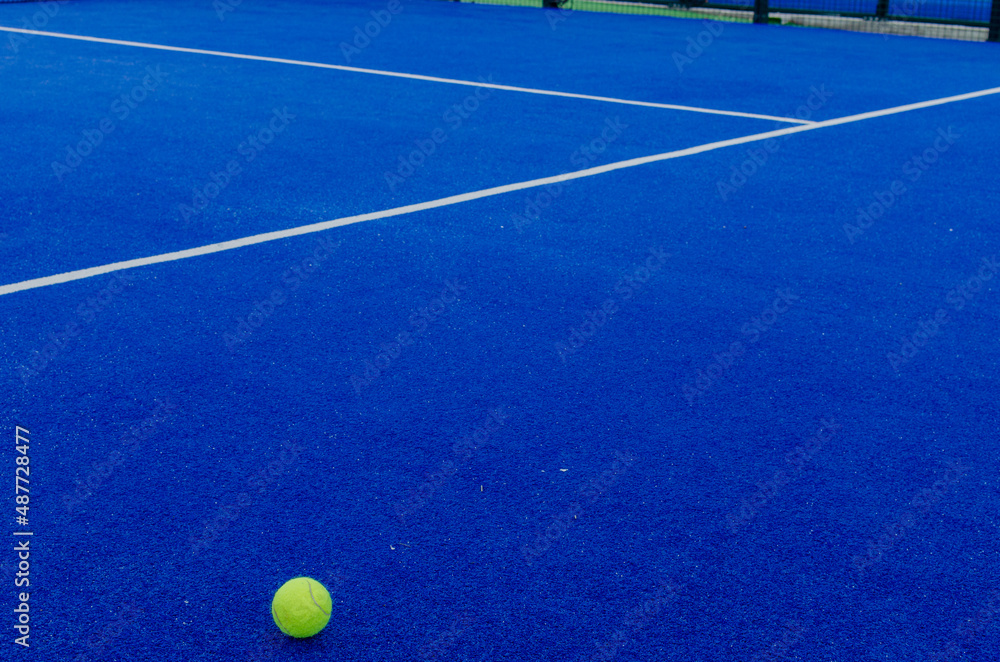a ball on the surface of a blue paddle tennis court