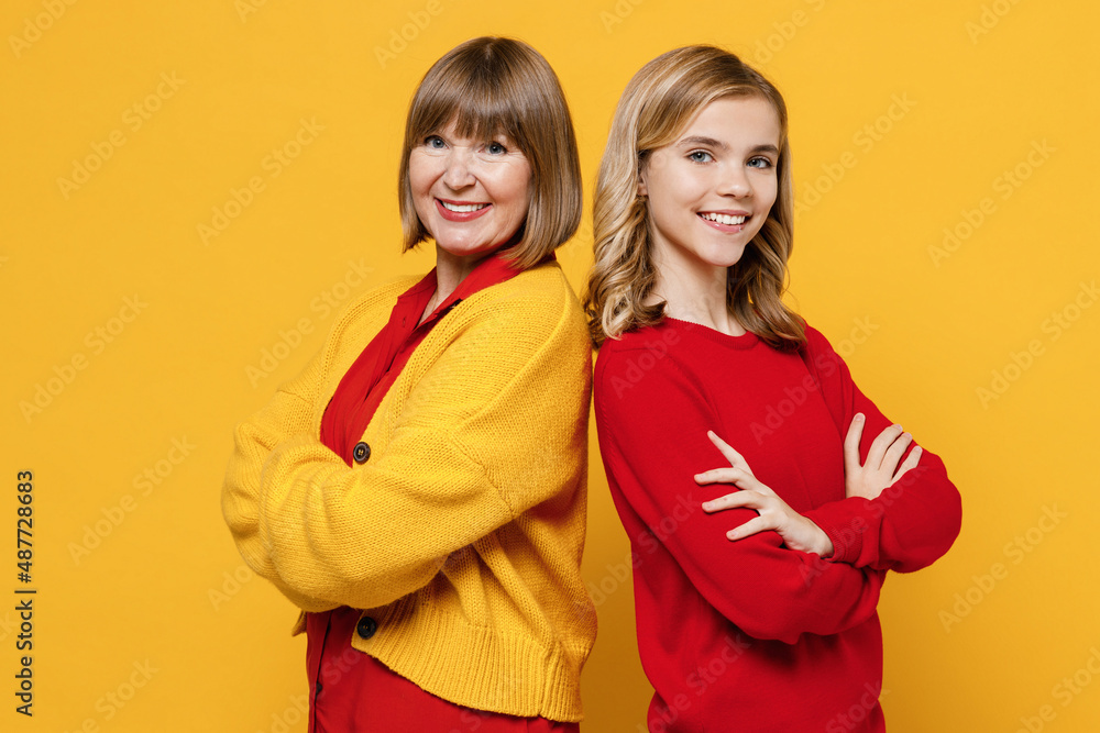 Happy fun smiling woman wear red shirt have fun with teenager girl 12-13 years old. Grandmother granddaughter hold hands crossed folded isolated on plain yellow background. Family lifestyle concept. Happy fun smiling woman wear red shirt have fun with teenager girl 12-13 years old. Grandmother granddaughter hold hands crossed folded isolated on plain yellow background. Family lifestyle concept.