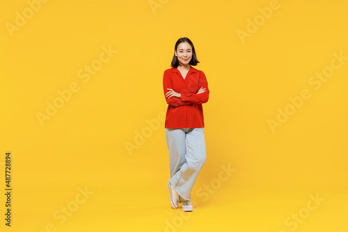 Fototapeta Naklejka Na Ścianę i Meble -  Full size body length vivid young woman of Asian ethnicity 20s years oldin casual clothes look camera smiling isolated on plain yellow background studio portrait. People emotions lifestyle concept