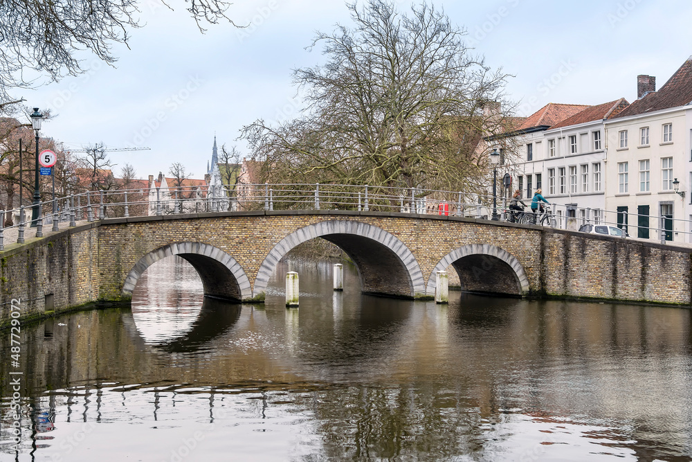 Old brick bridge on water canal of historic city of Bruges, Belgium