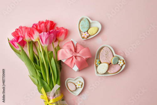 Happy Easter. Multi-colored pastel easter cookies gingerbread  gift box seasonal flowers tulips on pink background. Easter concept  copy space  flyer  banner  coupon  greeting card  invitation