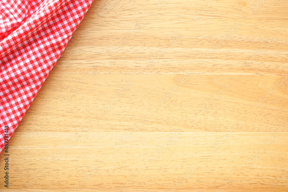 Wood table background with crumple pink plaid fabric or tablecloth in the corner Wood table background with crumple pink plaid fabric or tablecloth in the corner