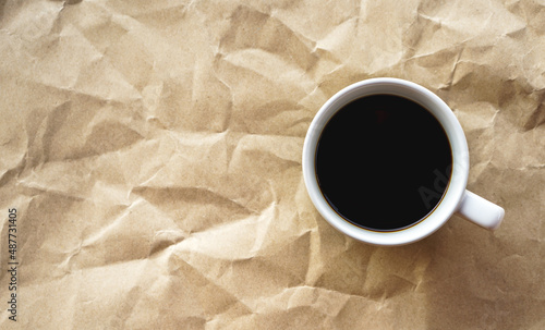 Top view of black coffee cup on crumple brown paper with copy space