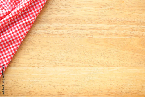 Wood table background with crumple pink plaid fabric or tablecloth in the corner 