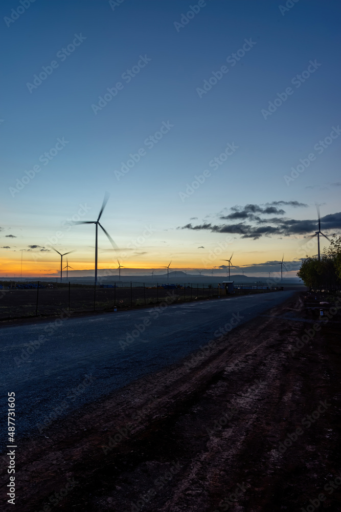Wind turbine farm and agricultural fields on a summer day. Wind electricity generator in sunset sky, power plant, wind efficiency. Wind turbine farm and agricultural fields on a summer day. Wind electricity generator in sunset sky, power plant, wind efficiency.