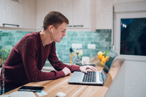 Redhead man working on laptop in a kitchen at home © Zamrznuti tonovi