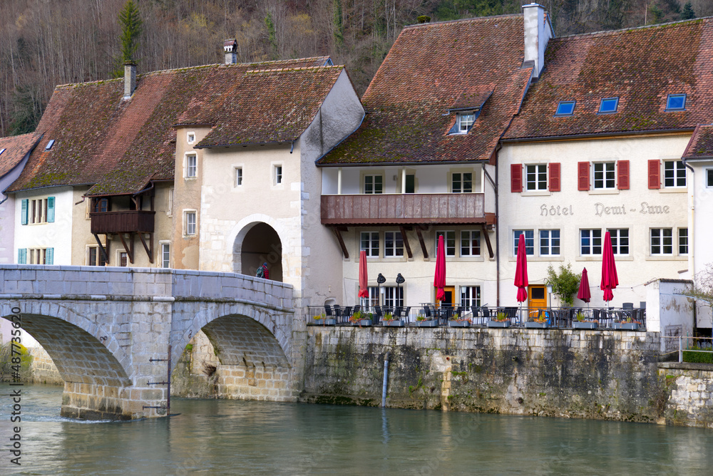 Chalk stone bridge over the river Doubs at little medieval town St-Ursanne, Canton Jura, on a sunny winter morning. Photo taken February 7th, 2022, Saint-Ursanne, Switzerland.