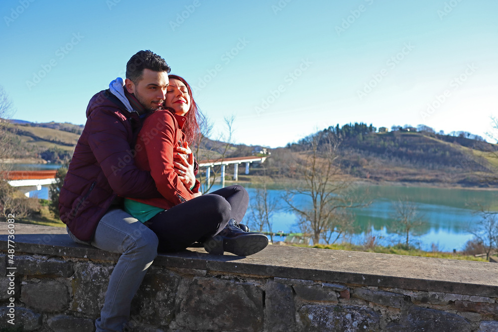 young caucasian couple hugs each other by the lake, romantic scene, love concept young caucasian couple hugs each other by the lake, romantic scene, love concept