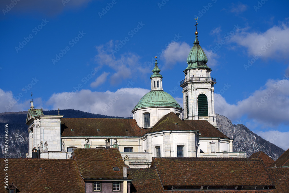 Historic colorful house facades at medieval alley with cathedral St. Ursen in the background at the old town of Solothurn on a sunny winter day. Photo taken February 7th, 2022, Solothurn, Switzerland.