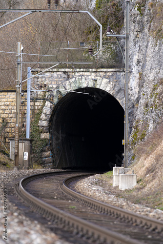 Empty railway tracks with tunnel portal near railway station of St-Ursanne on a cloudy winter day. Photo taken February 7th, 2022, Saint-Ursanne, Switzerland.