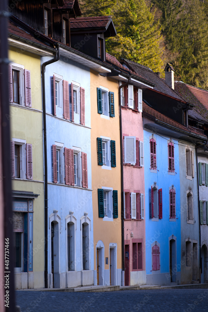Naklejka premium Beautiful historic houses with colorful facades at the little medieval town of St-Ursanne, Canton Jura, on a winter morning. Photo taken February 7th, 2022, Saint-Ursanne, Switzerland.