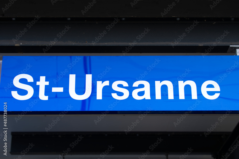 Blue sign at railway station of St-Ursanne on a cloudy winter day. Photo taken February 7th, 2022, Saint-Ursanne, Switzerland. Blue sign at railway station of St-Ursanne on a cloudy winter day. Photo taken February 7th, 2022, Saint-Ursanne, Switzerland.